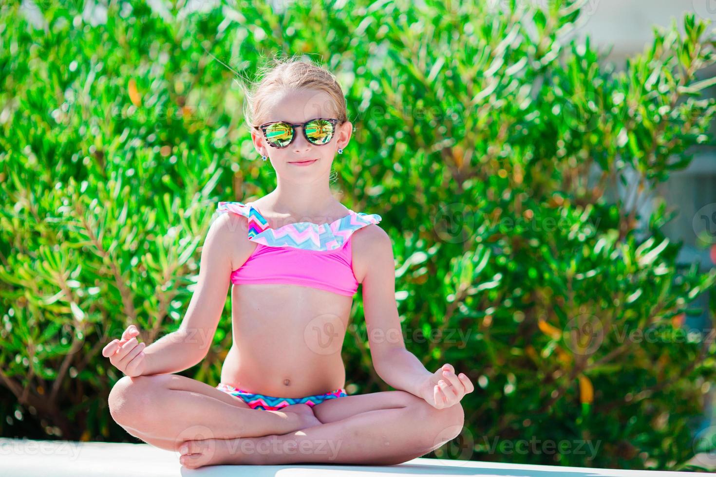 Portrait of adorable little girl in yoga outdoor on vacation photo