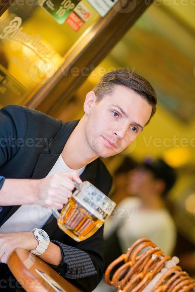 joven con cerveza y pretzels suaves salados en el bar deportivo de cerveza foto