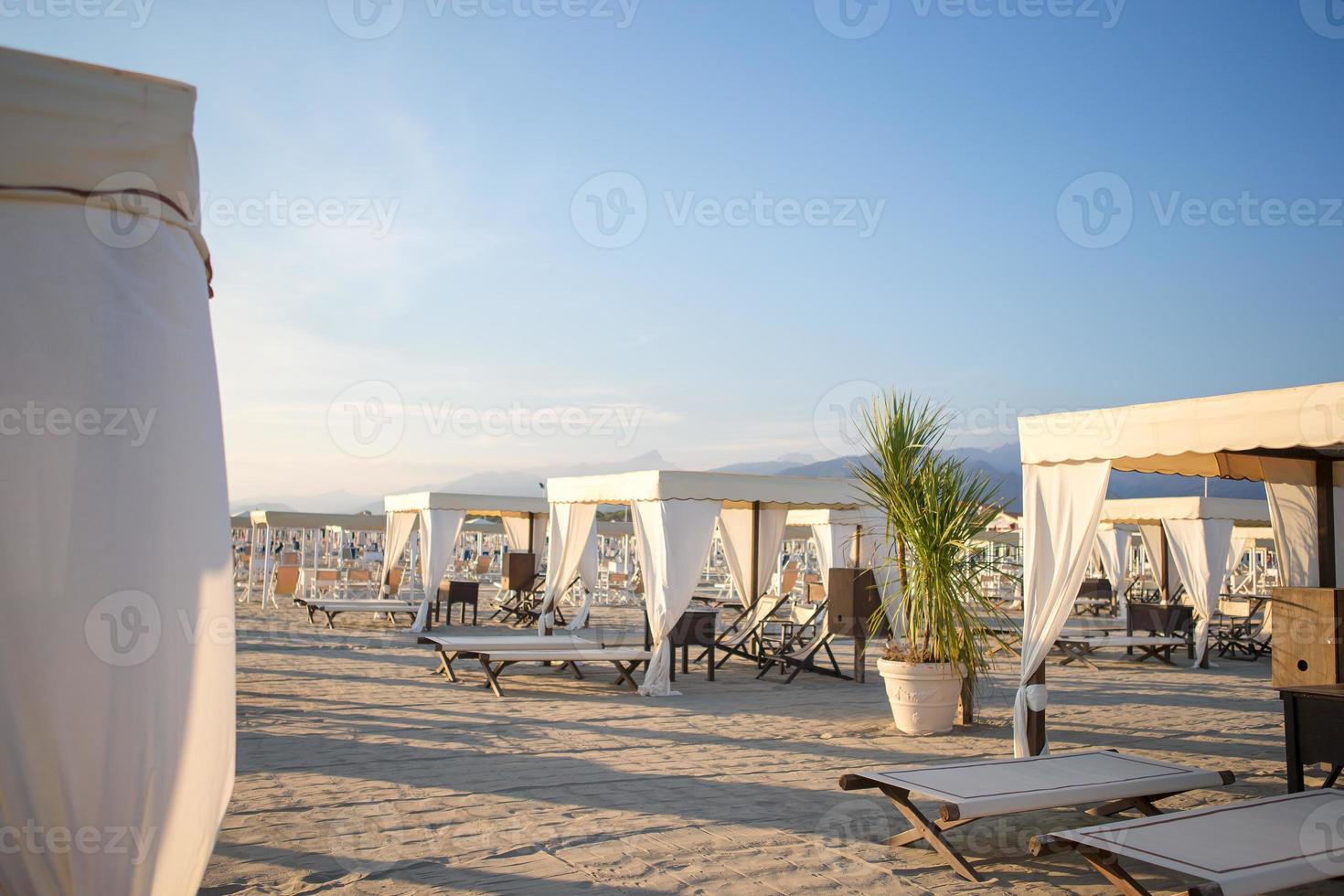 tumbonas de madera en la luz suave de la tarde. tumbonas en la famosa playa de arena italiana en forte dei marmi foto