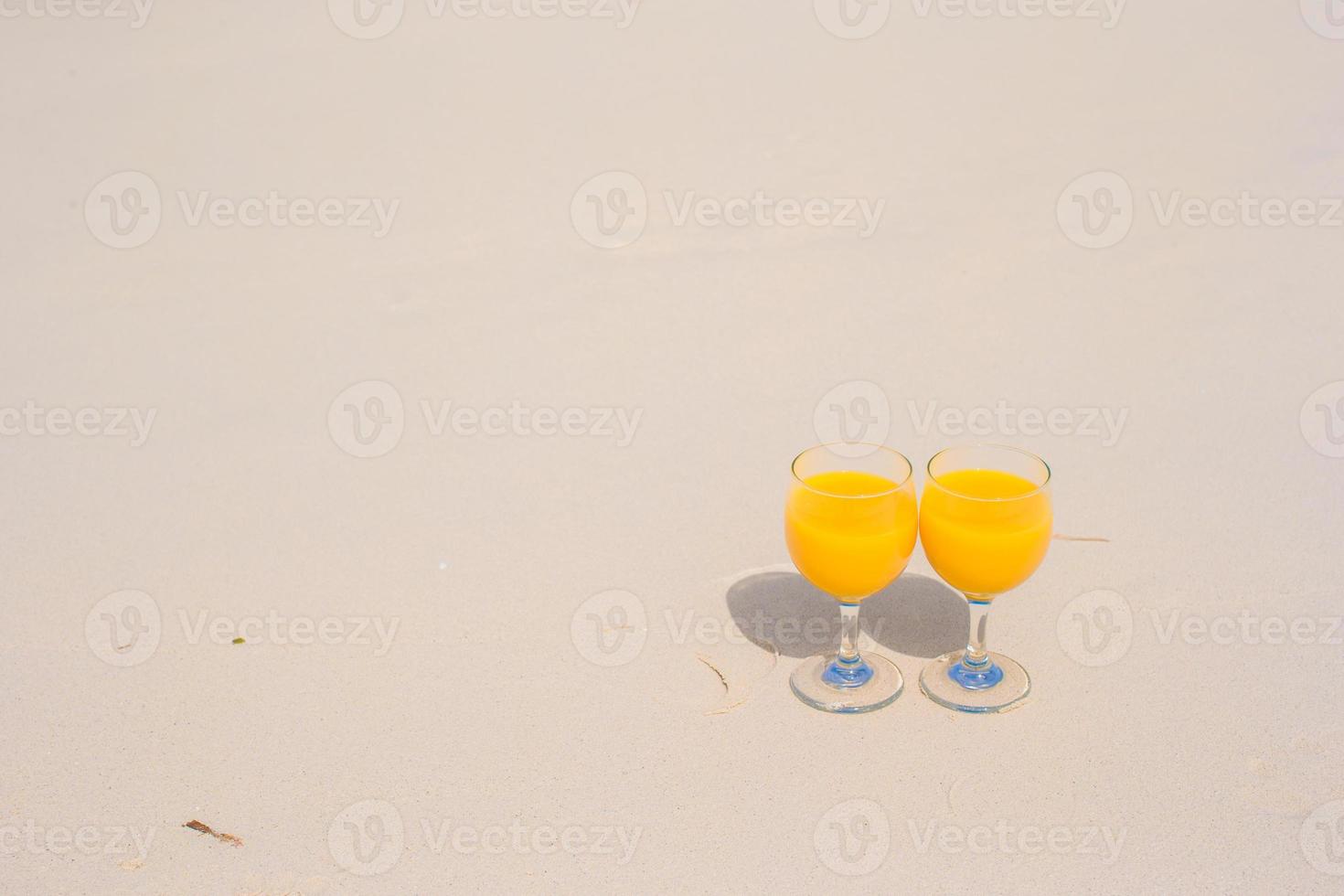 Two glasses of orange juice on tropical white beach photo