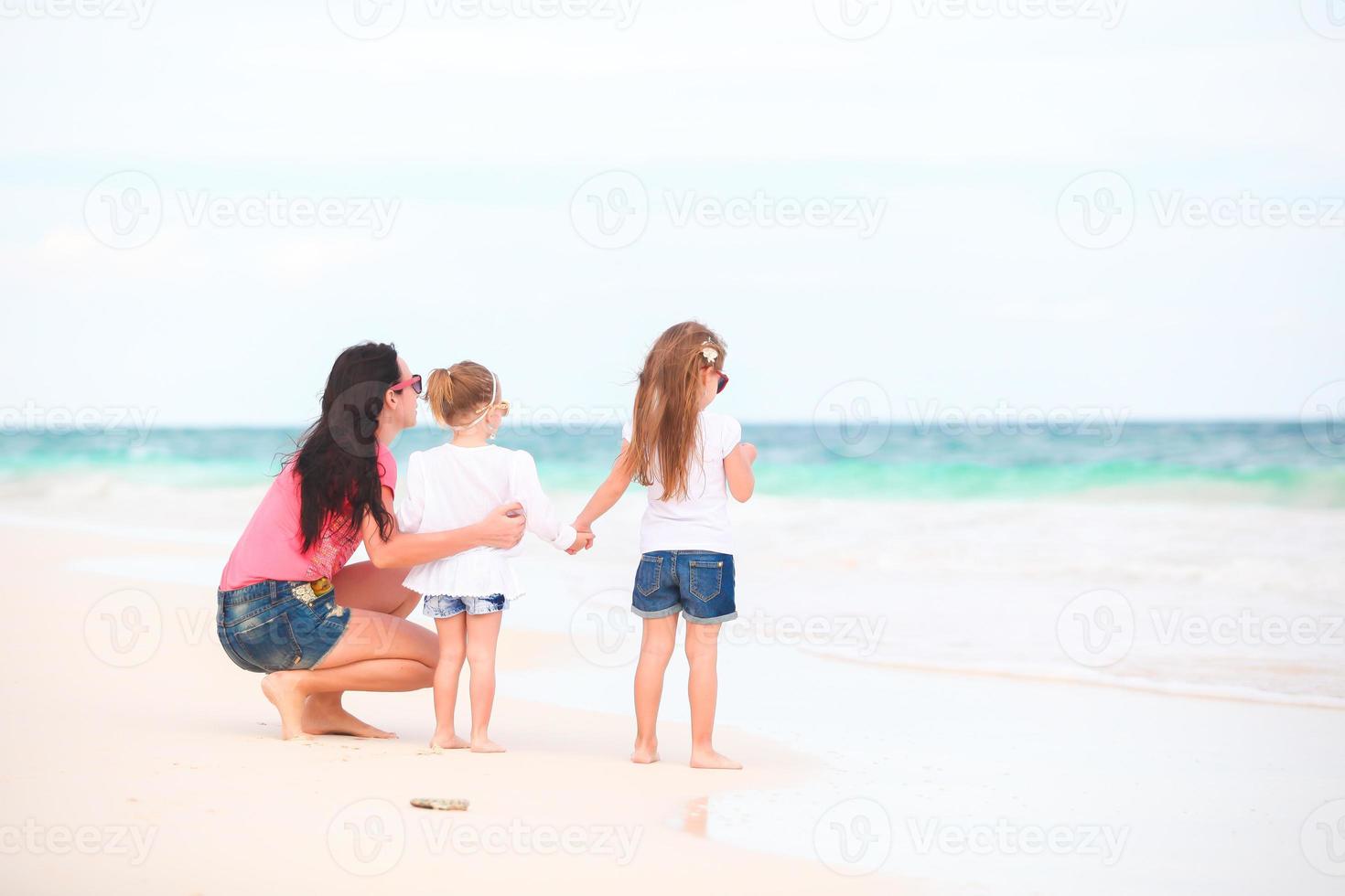 adorables niñas y madre joven en playa blanca foto