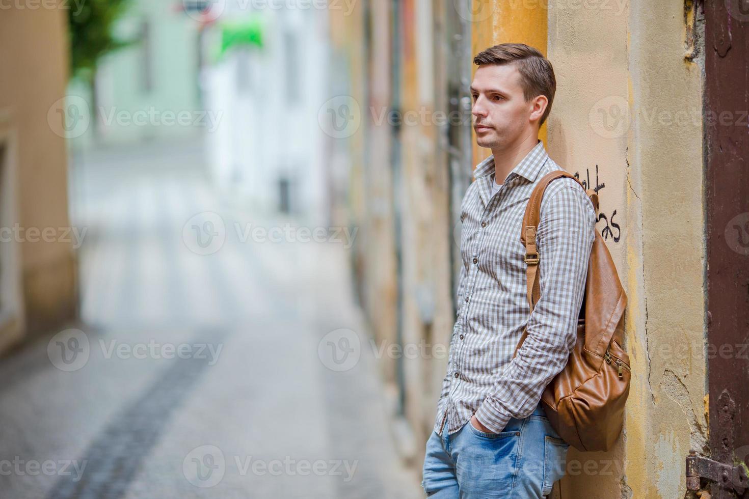 turista caucásico caminando por las calles desiertas de europa. joven urbano de vacaciones explorando la ciudad europea foto