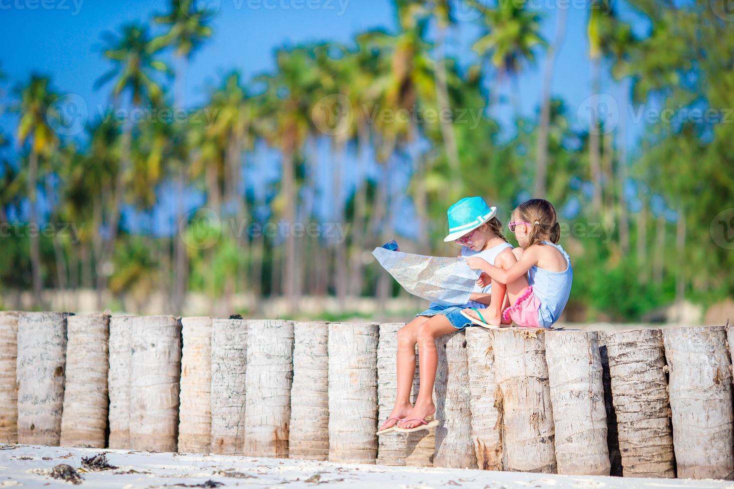 Adorable little girls with big map of island on beach photo