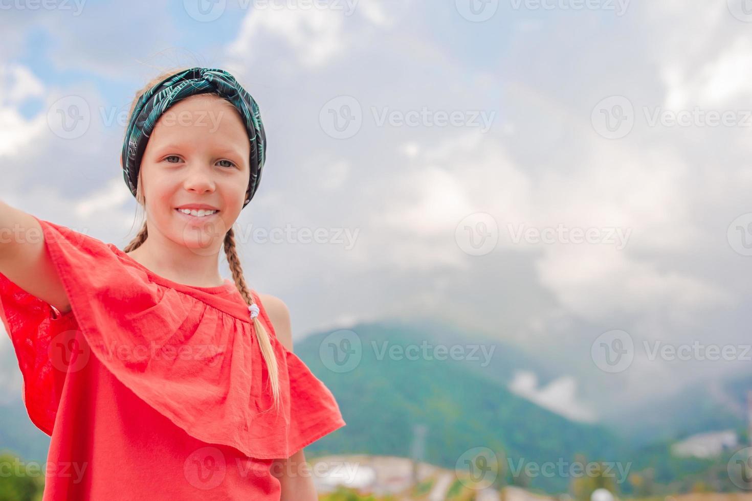 Beautiful happy little girl in mountains in the background of fog photo