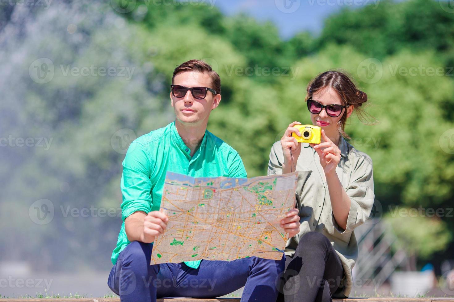 Young tourist friends traveling on holidays in Europe smiling happy. Caucasian couple with city map in search of attractions photo