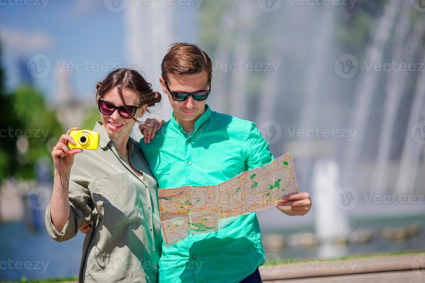 jóvenes amigos turistas que viajan de vacaciones en europa sonriendo felices. chica tomando fotos en el parque y hombre con mapa de la ciudad en busca de atracciones