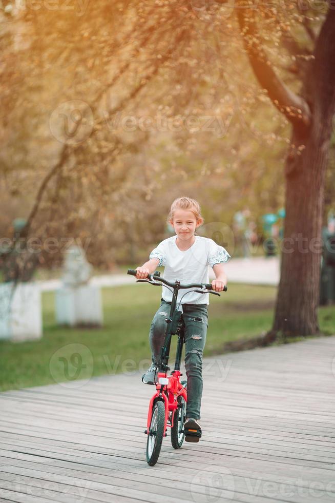 Adorable girl riding a bike at beautiful summer day outdoors photo