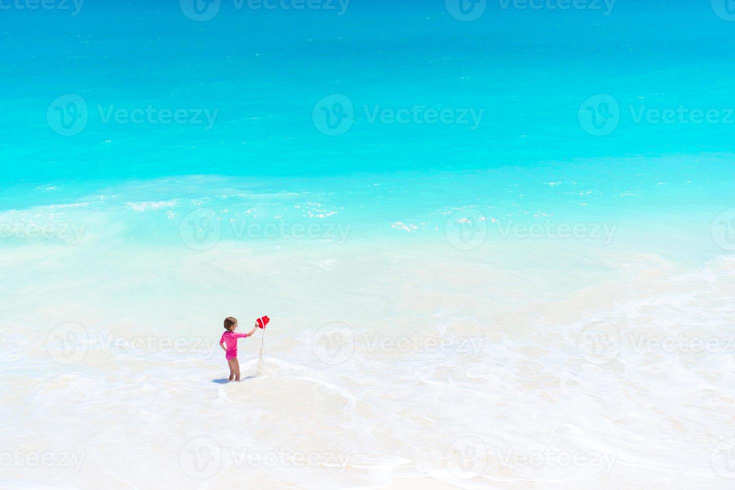 Little girl at tropical white beach having a lot of fun with toys photo