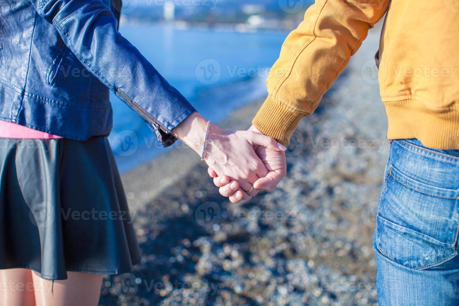 Rear view of a man and woman holding hands on the sea background photo