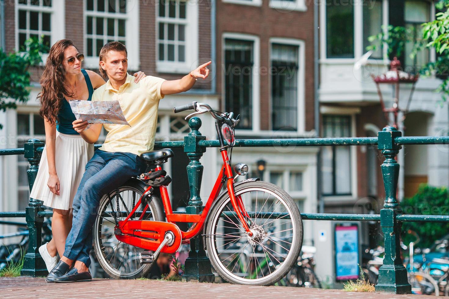 Young happy caucasian couple on bikes in old streets in Amsterdam photo