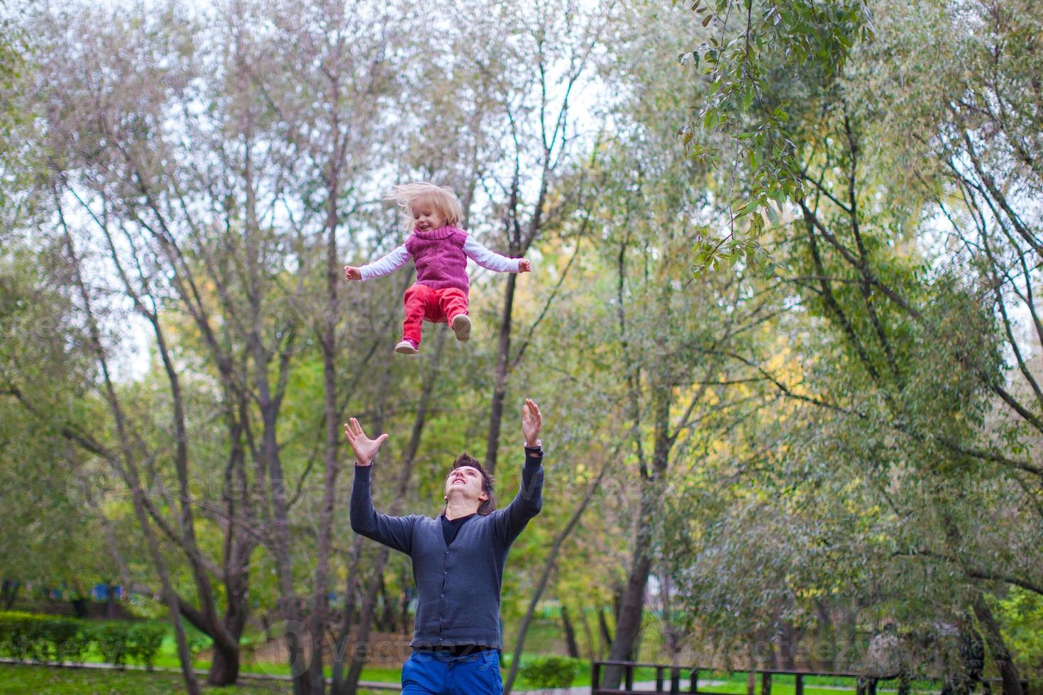 el joven padre con su linda niña se divierte al aire libre en otoño foto