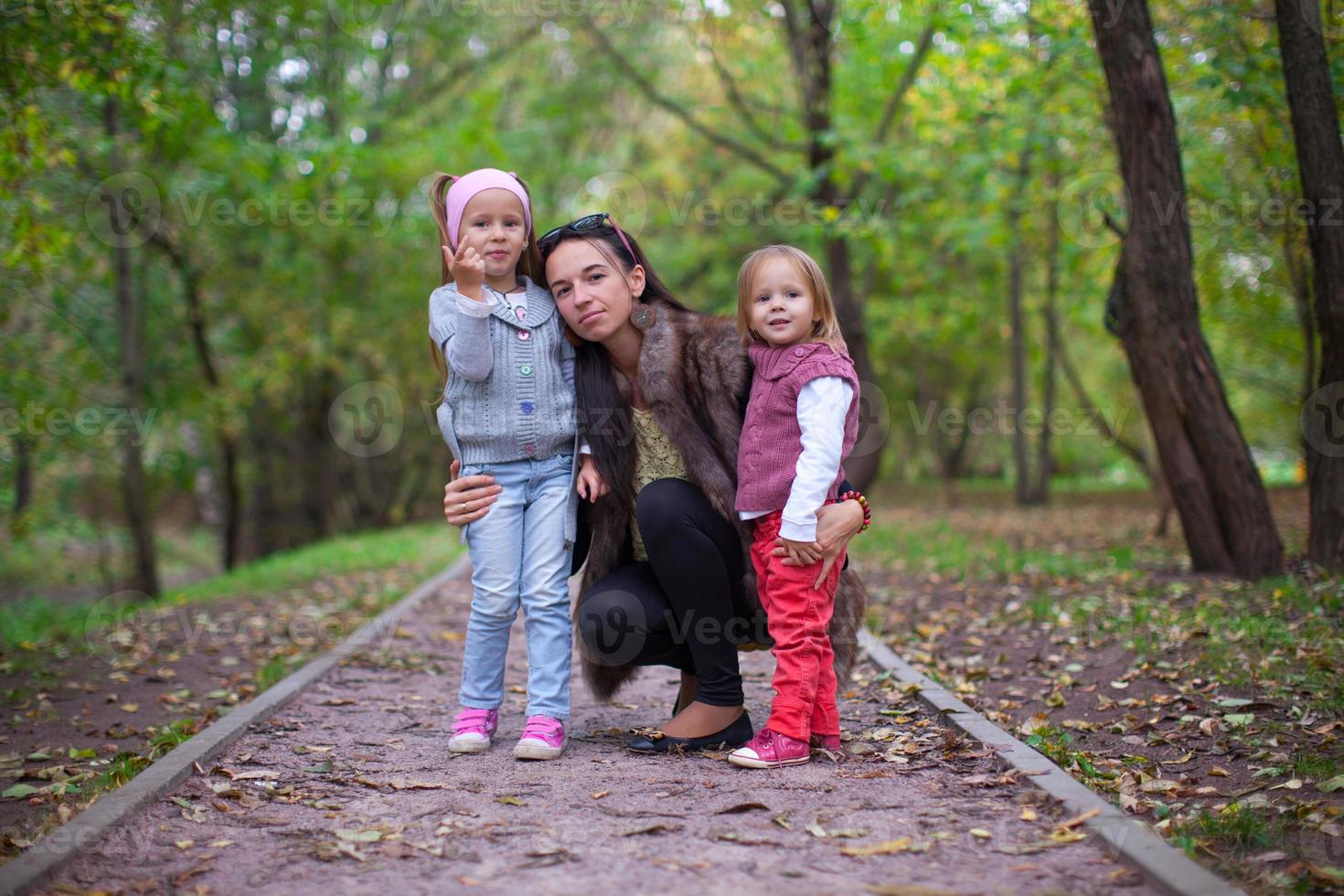 Young mother with her little daughters looking to camera oudoor photo