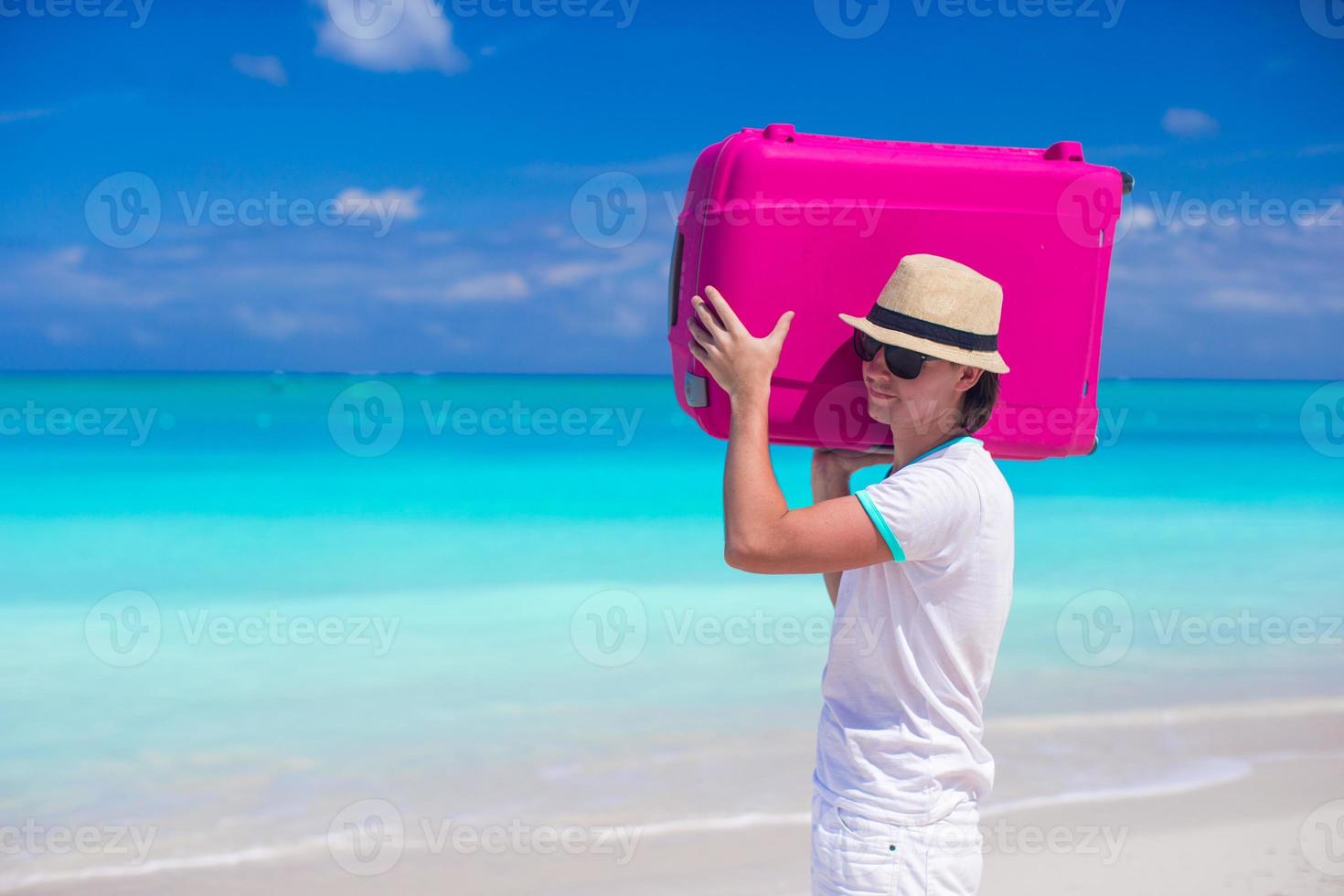 Portrait of a young man carrying his luggage on the beach photo