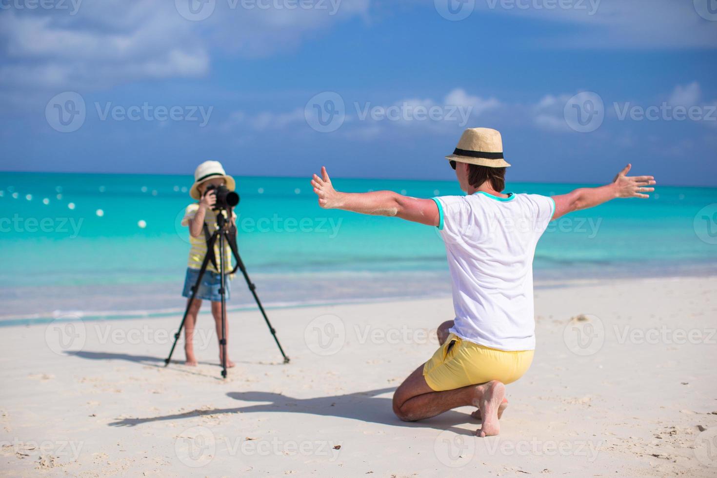 Little adorable girl making photo of her young father at exotic beach