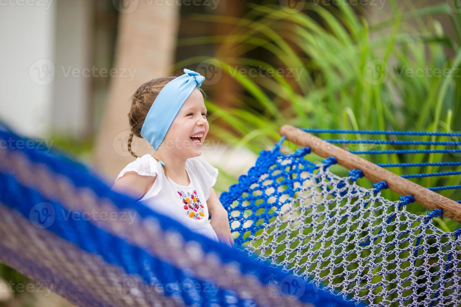 Adorable little girl swinging in hammock at beach photo
