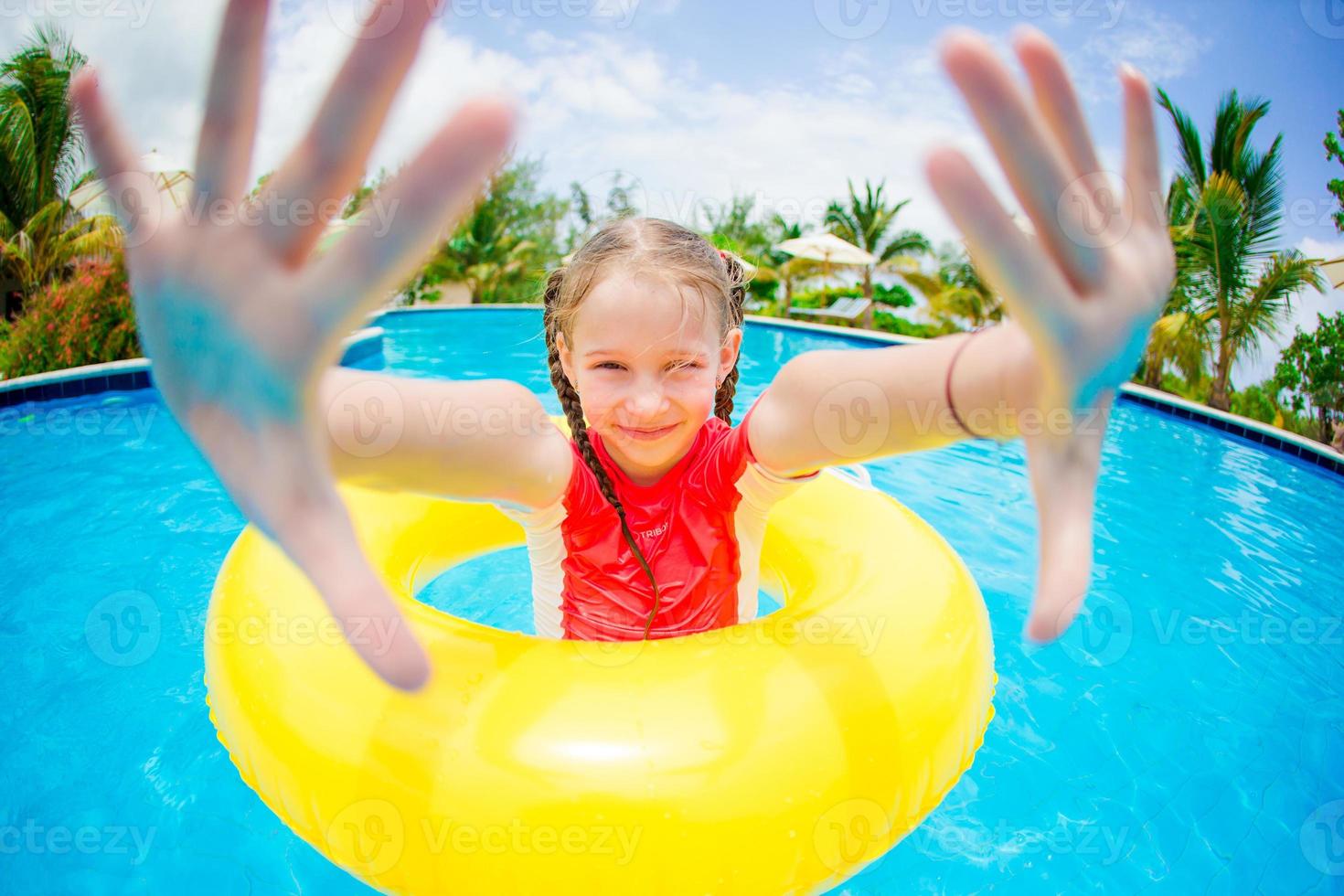 Portrait of happy child with inflatable rubber circle having fun in swimming pool photo