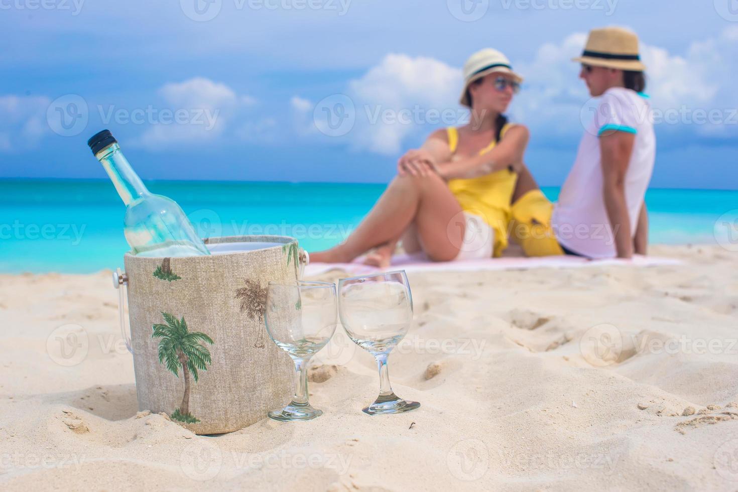 Bottle of wine and two glasses background happy couple at beach photo