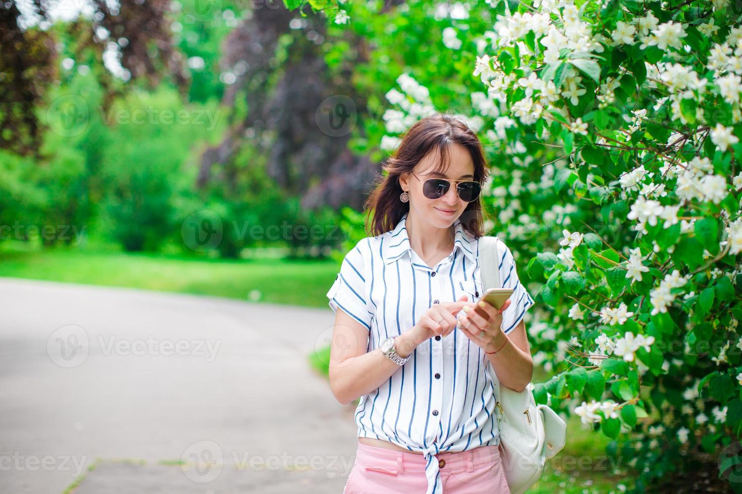 Tourist girl sending messgae by smartphone on summer holidays. Young attractive tourist with mobile phone outdoors enjoying holidays travel destination in tourism and exploring concept photo