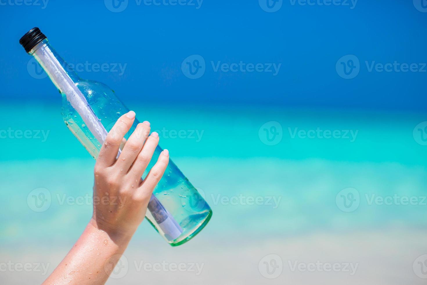 Bottle with a message in the hand background blue sky photo