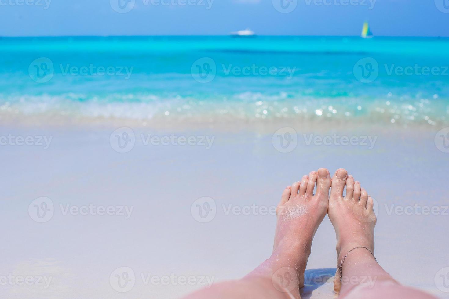 Close up of female feet on white sandy beach photo
