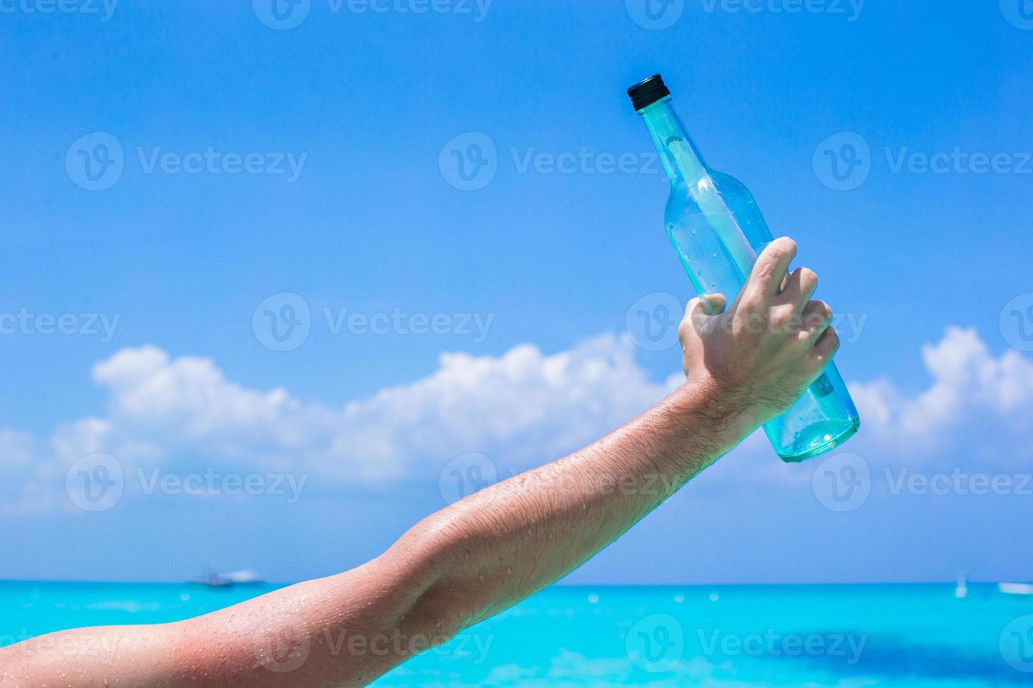 Bottle with a message in the hand background blue sky photo