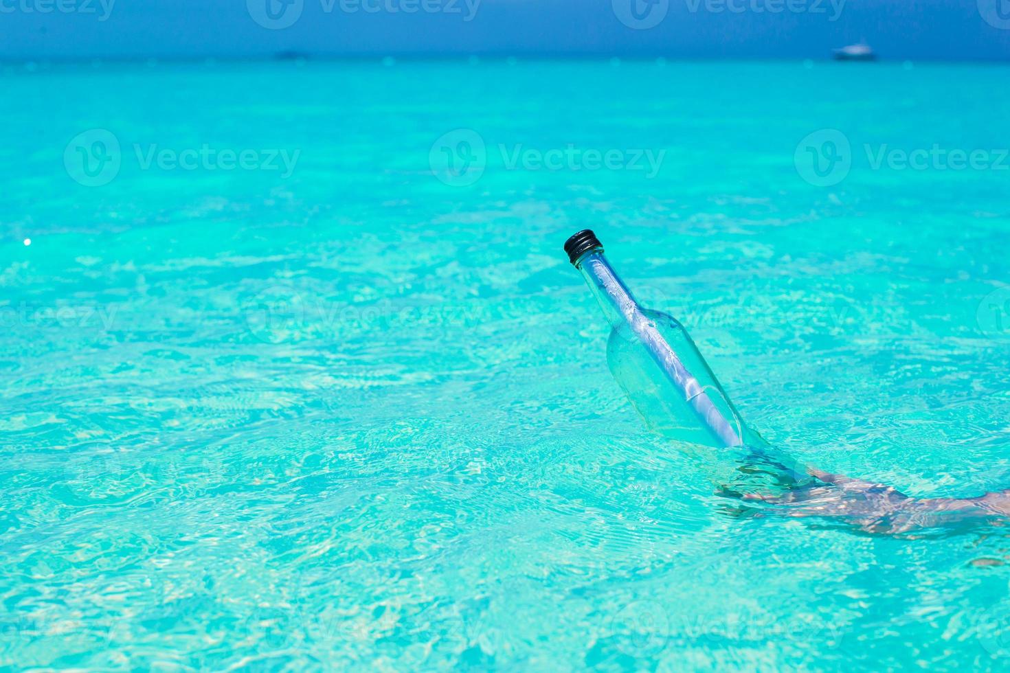 Bottle with a message in the hand background blue sky photo