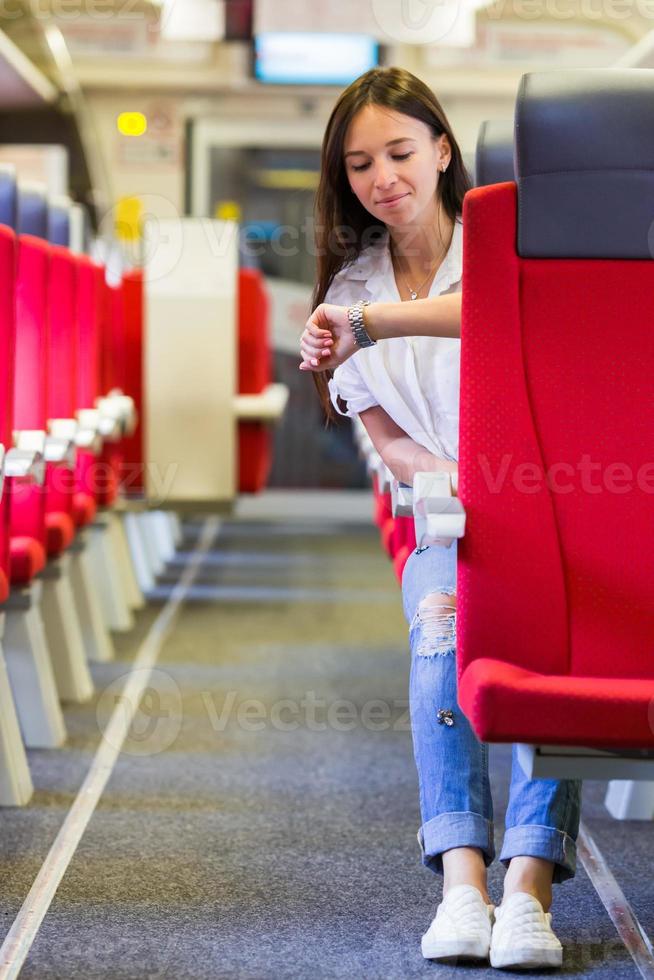 Young happy girl looking at watch traveling by train photo