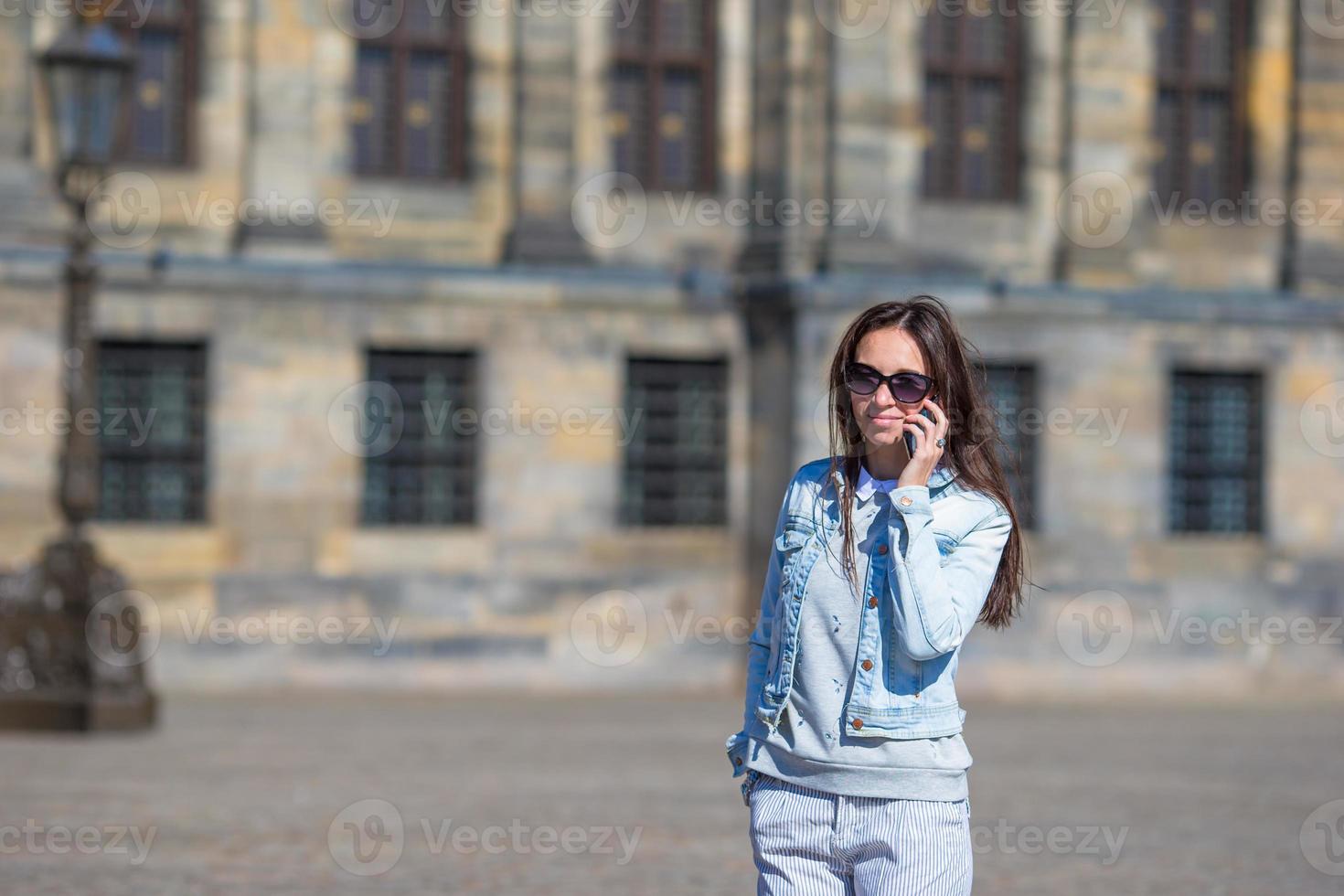 joven mujer caucásica hablando por teléfono celular en calles antiguas en ciudad europea foto