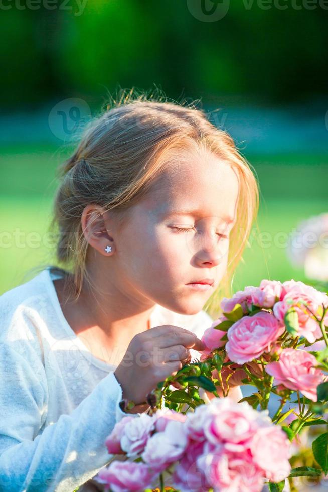 niña adorable que huele flores de colores al aire libre foto