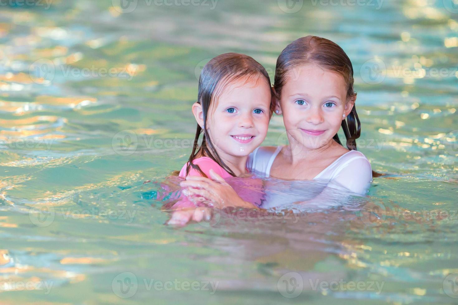 Adorable little girls in swimming pool on summer vacation photo