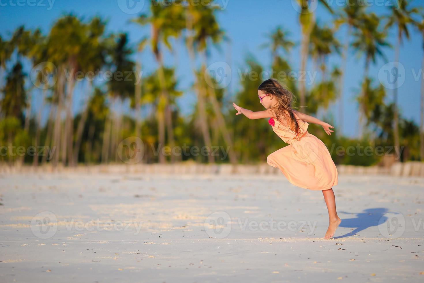 Adorable little girl having fun at beach vacation photo