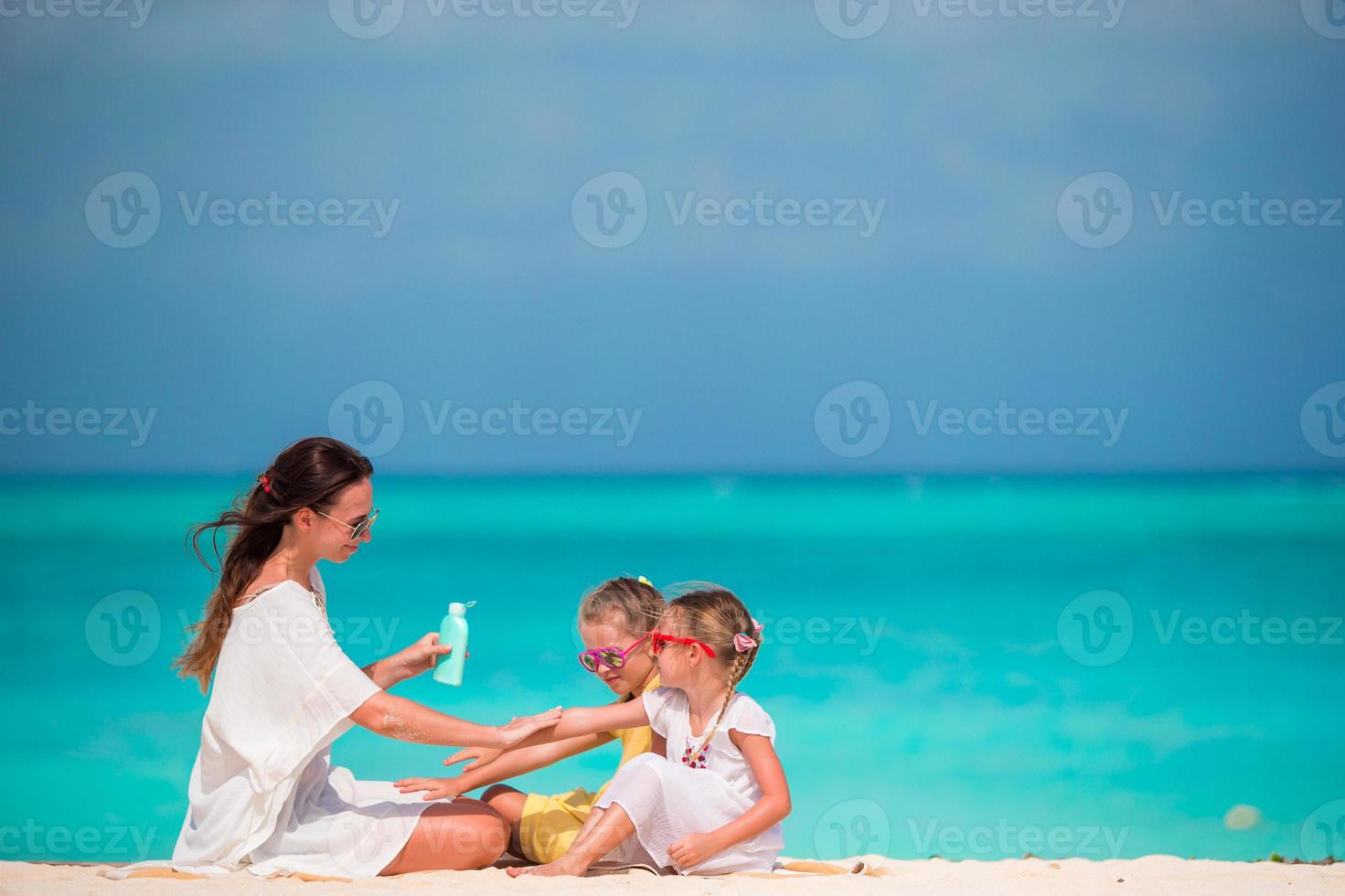 Young mother applying sunscreen on her kids photo