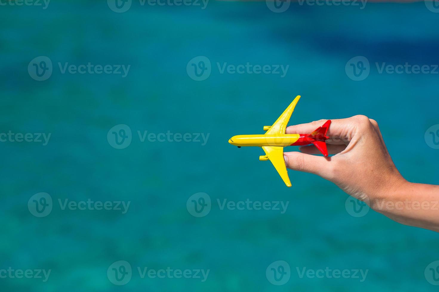 Small homemade plane in female hand on background of the sea photo