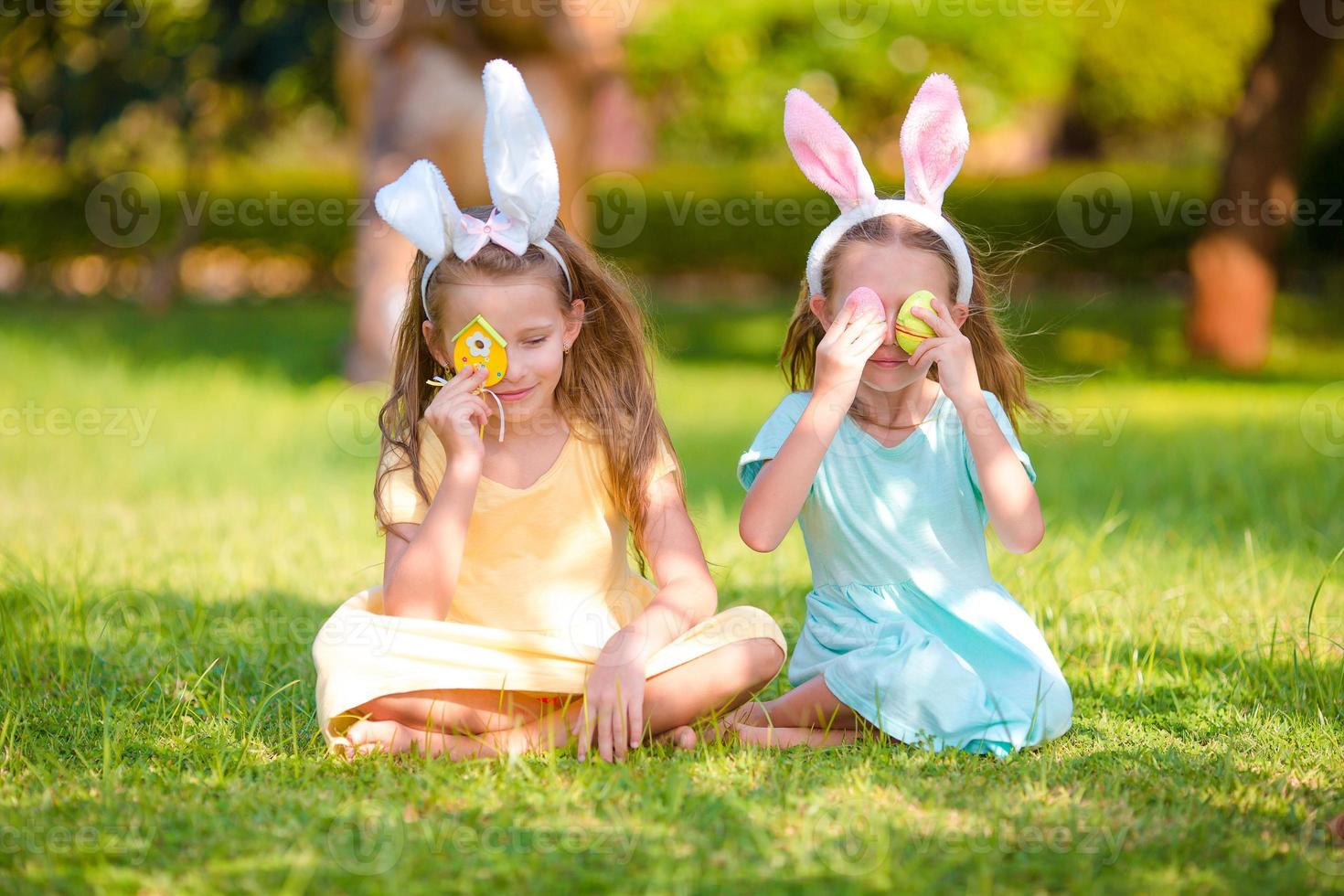 Adorable little girls wearing bunny ears on Easter day outdoors photo