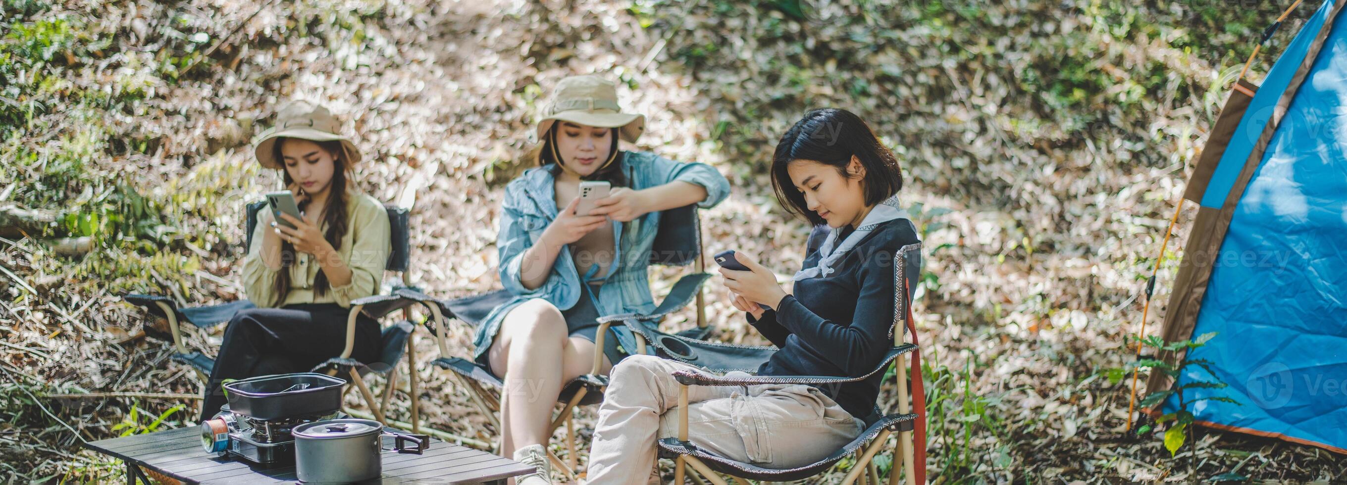 Group of girl friends with smartphone while camping in park photo