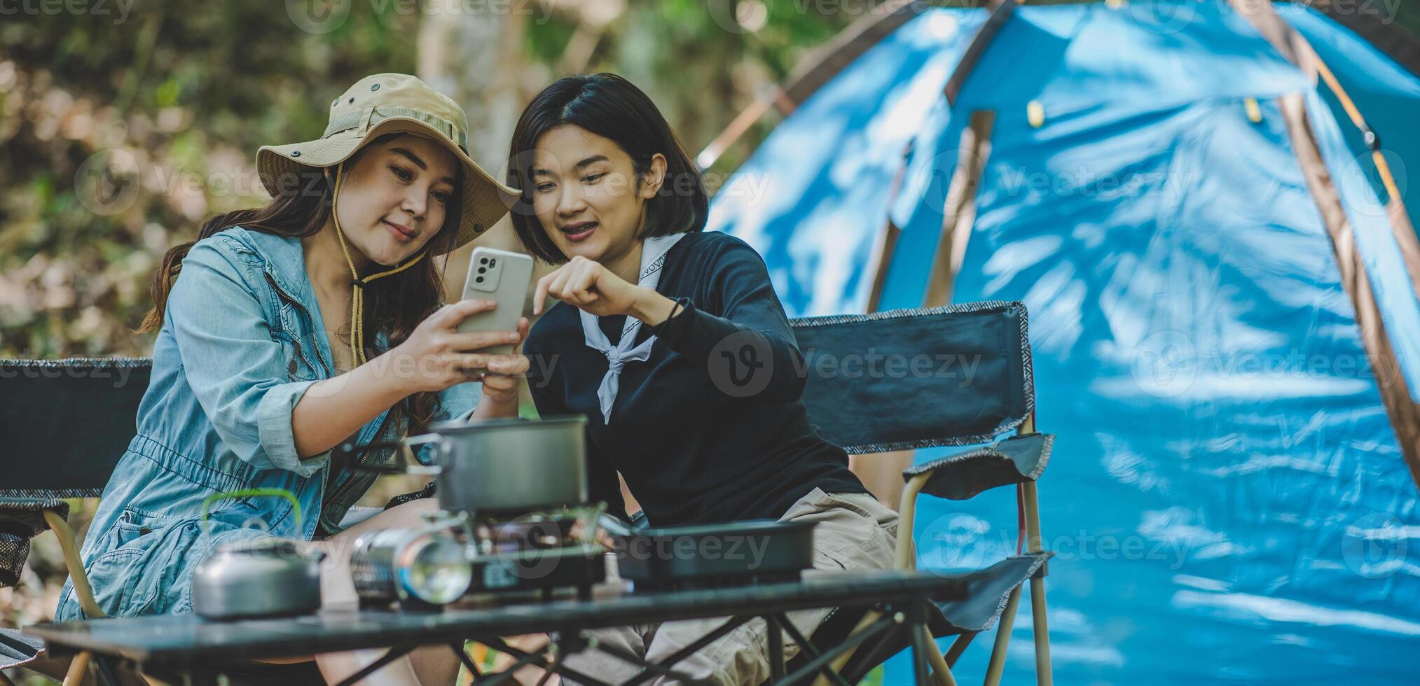 Asian pretty woman and friend use smartphone selfie on camping photo