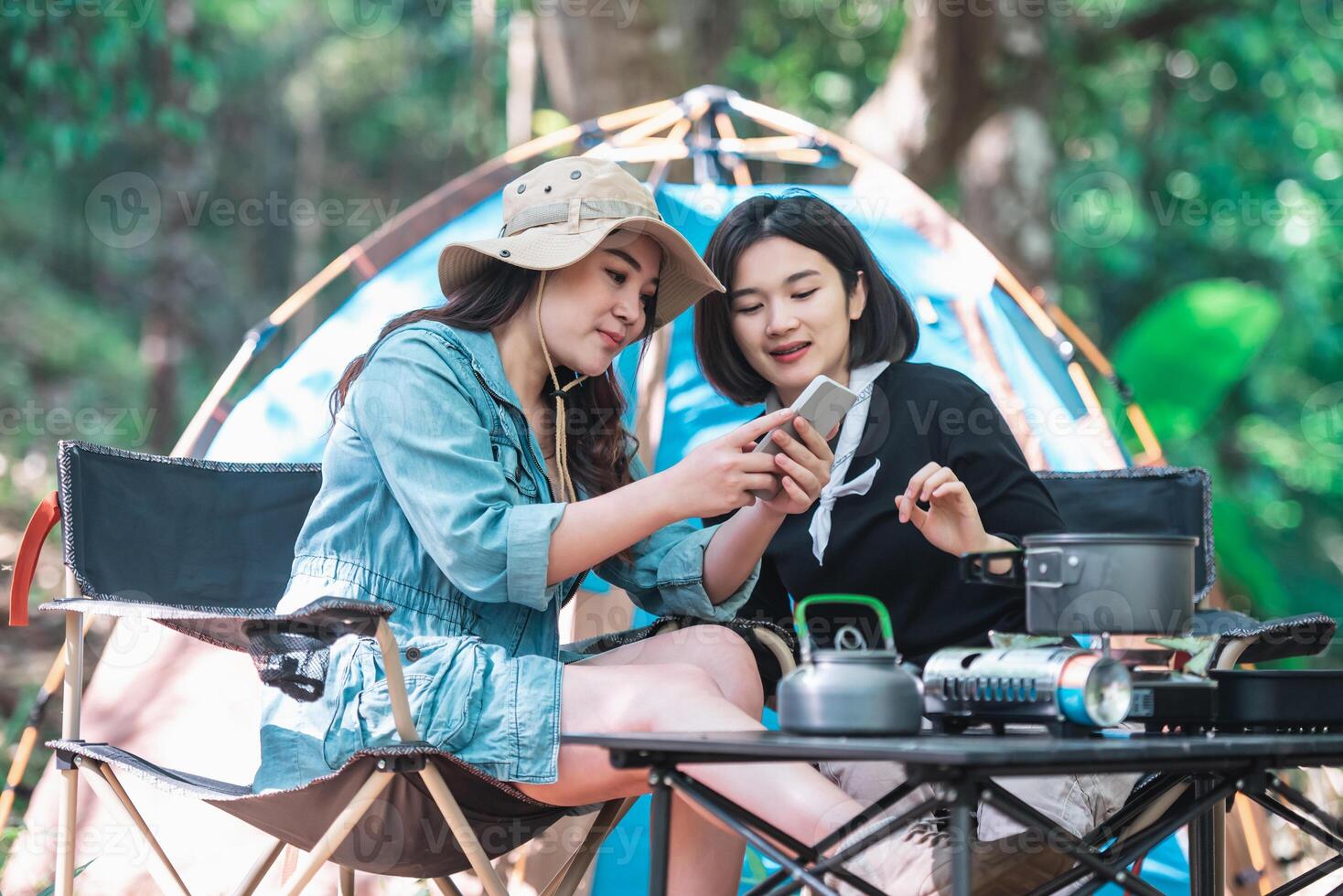 Asian pretty woman and girlfriend use smartphone selfie on camping photo
