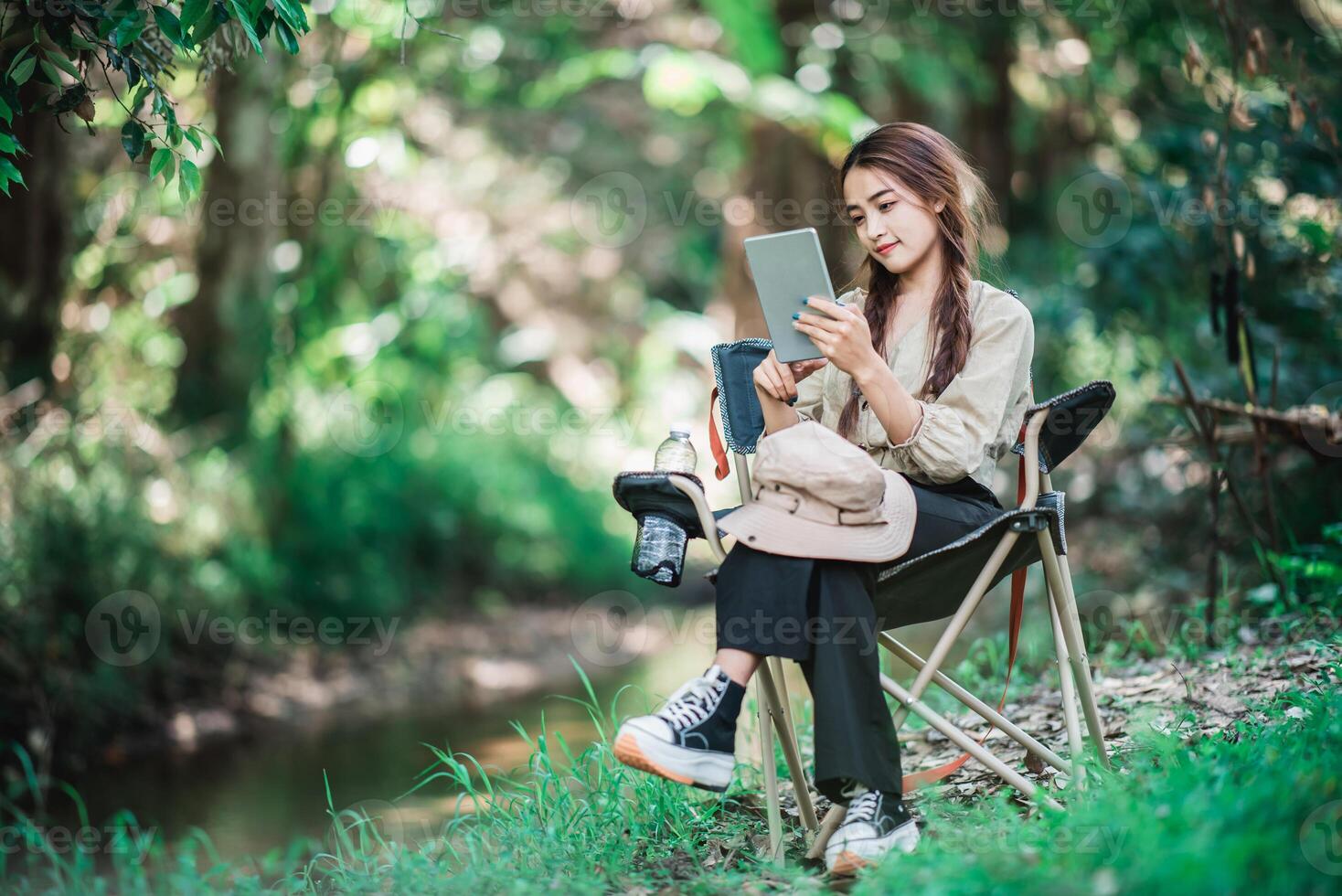 mujer joven usa videollamada de tableta mientras acampa en el parque foto