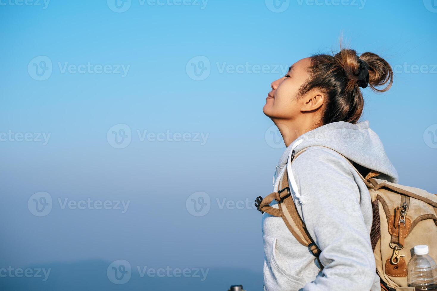 Portrait of Asian young tourist woman is hiking on the top of the mounting and looking at a beautiful landscape with copy space photo