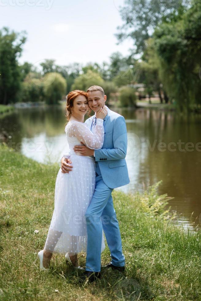bride in a light wedding dress to the groom in a blue suit photo