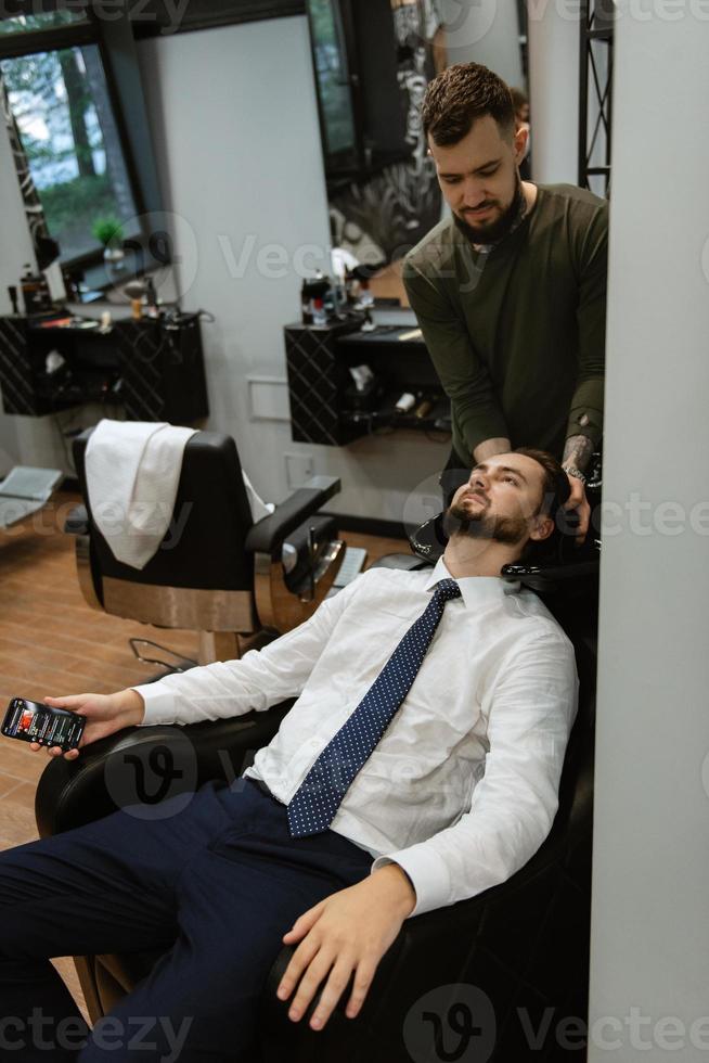 bearded man cutting his beard in the barbershop photo