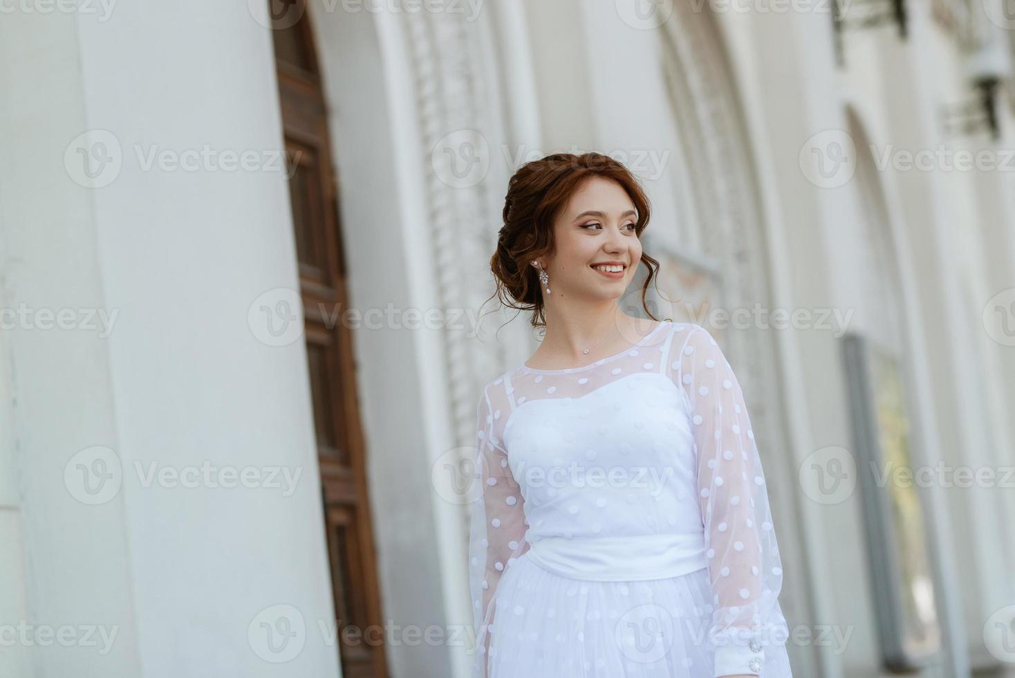 portrait of a young bride girl in a light dress in an urban environment photo