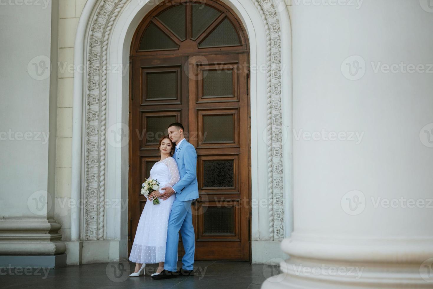 bride in a light wedding dress to the groom in a blue suit photo