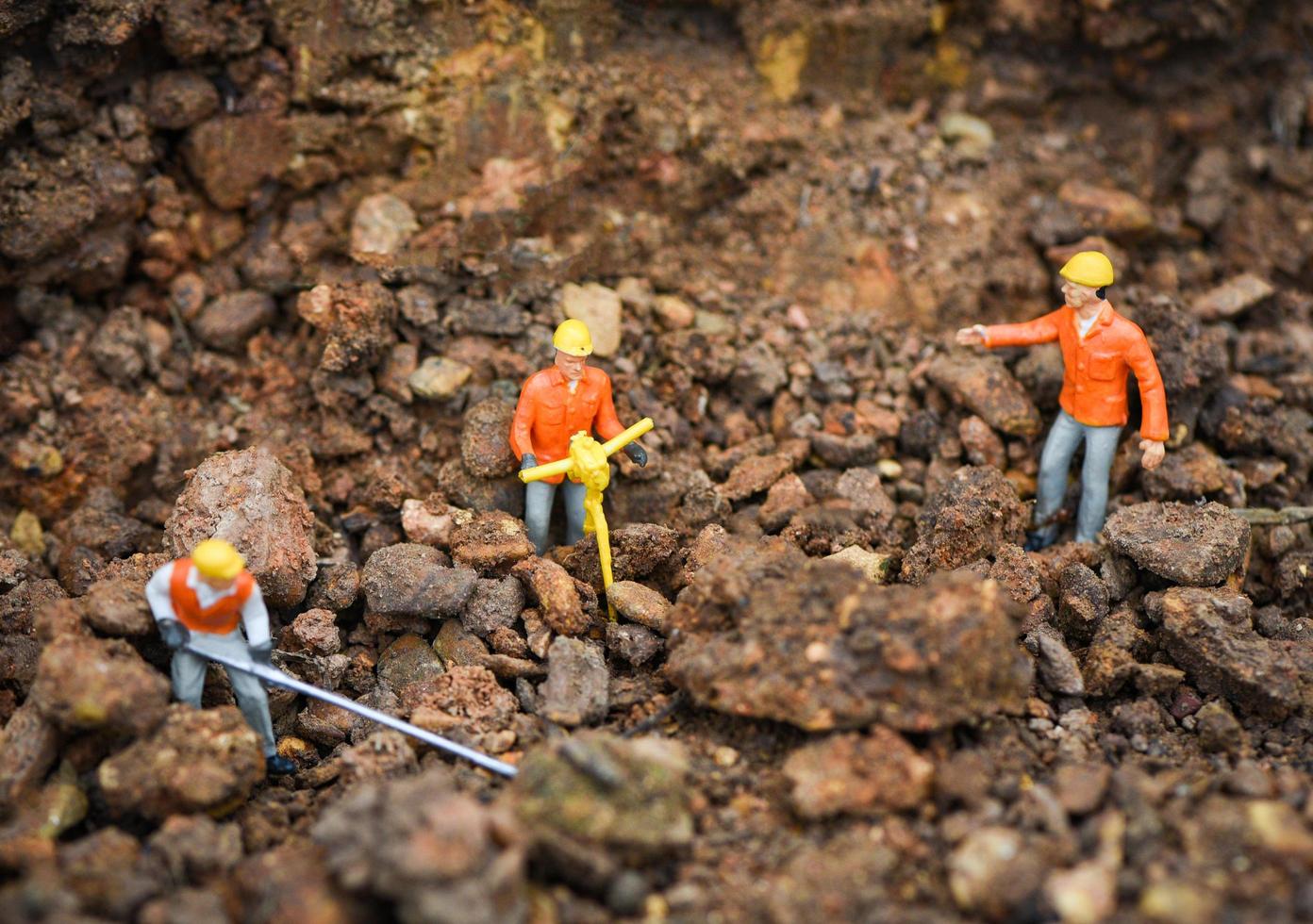 Construction worker concept figurines working digging ground soil with teams engineer looking photo