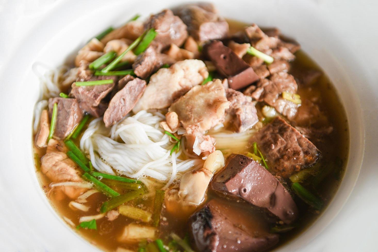 Tazón de fideos deliciosos sopa de fideos vermicelli con verduras estofadas de cerdo en un tazón comida tradicional tailandesa y china de Asia, despojos de cerdo, intestinos de hígado de cerdo foto