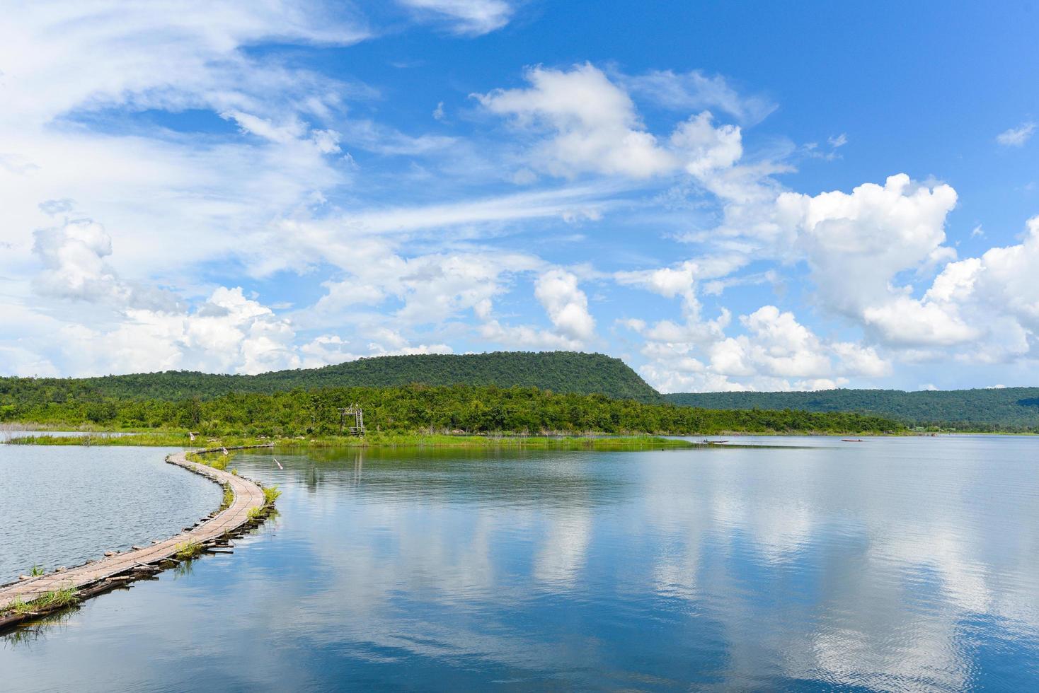 puerto en agua de río en Tailandia cielo azul con nubes hermoso y paisaje de fondo de montaña de la isla - puente de madera de bambú en la superficie del agua foto
