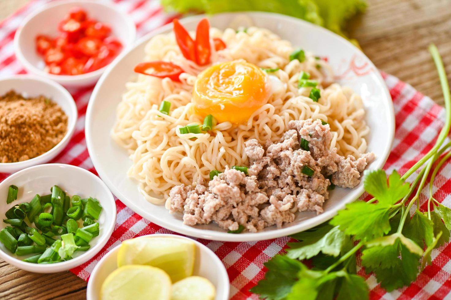 noodles plate with egg minced pork vegetable spring onion lemon lime lettuce celery and chili on table food , instant noodles cooking tasty eating with bowl noodle soup photo