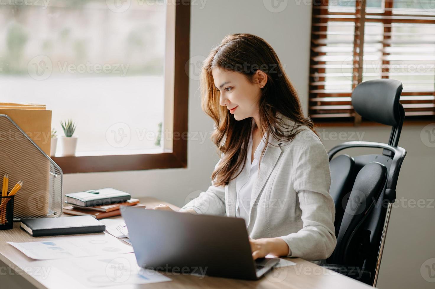 mujer de negocios asiática que trabaja en la oficina con documentos de bloc de notas, tableta y computadora portátil foto