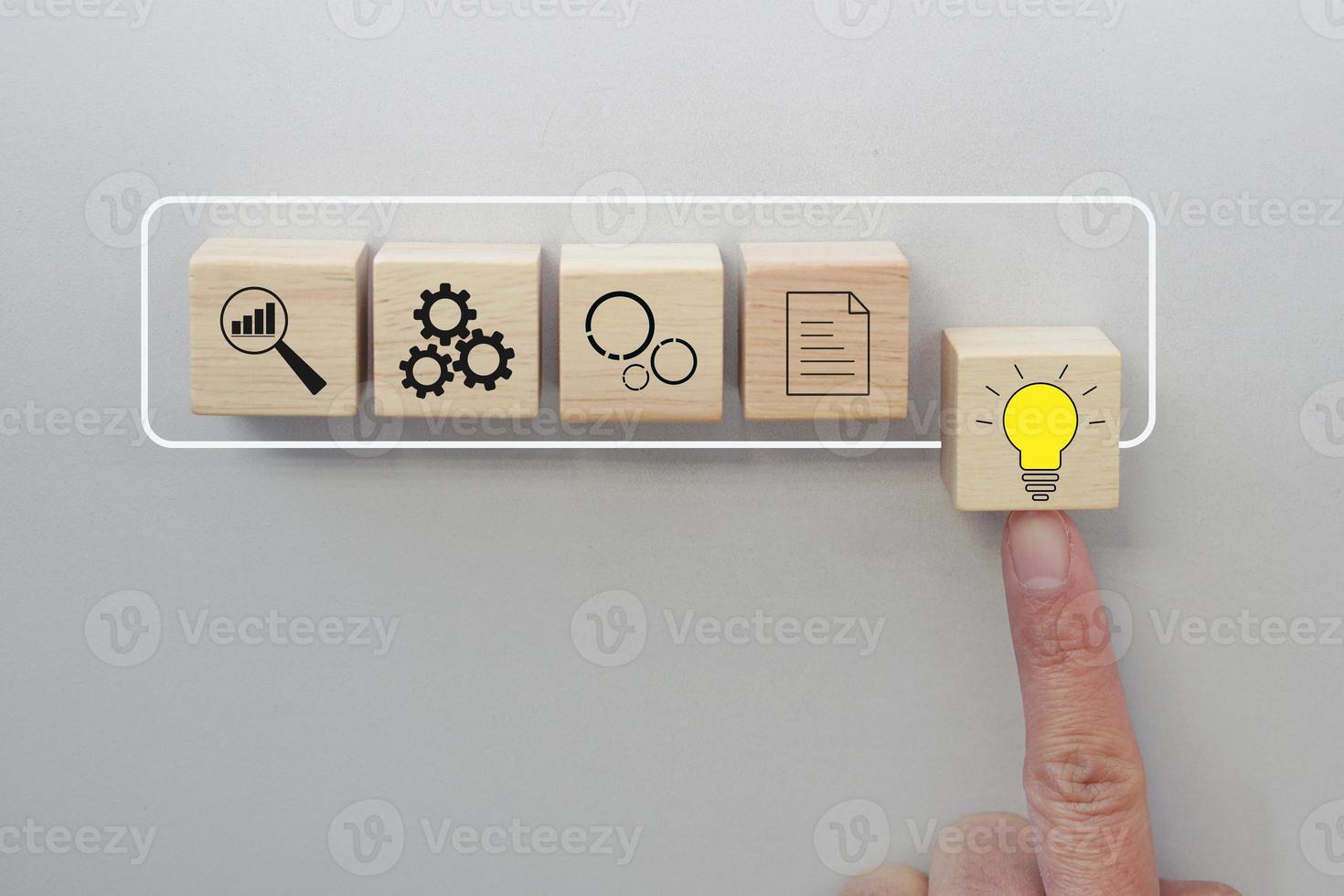 Finger pushing wooden cube with light bulb symbol on virtual infographic rectangle block. Progressive concept of business to success. photo