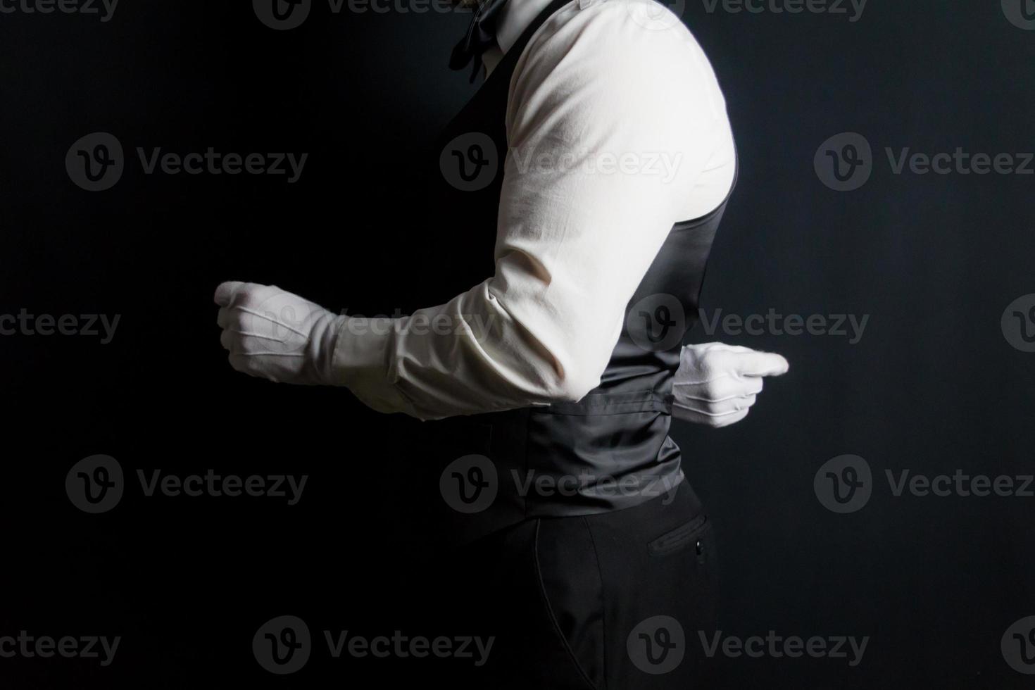 mayordomo de retrato de perfil o camarero con chaleco negro y guantes blancos de pie en elegante atención. a su servicio. foto